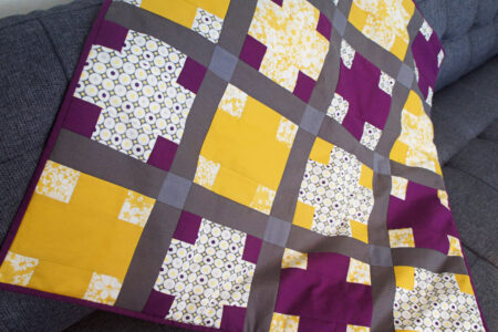 Lilla og gult patchwork babytæppe med krydser
