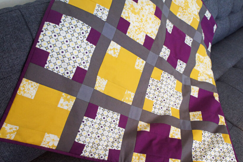 Lilla og gult patchwork babytæppe med krydser